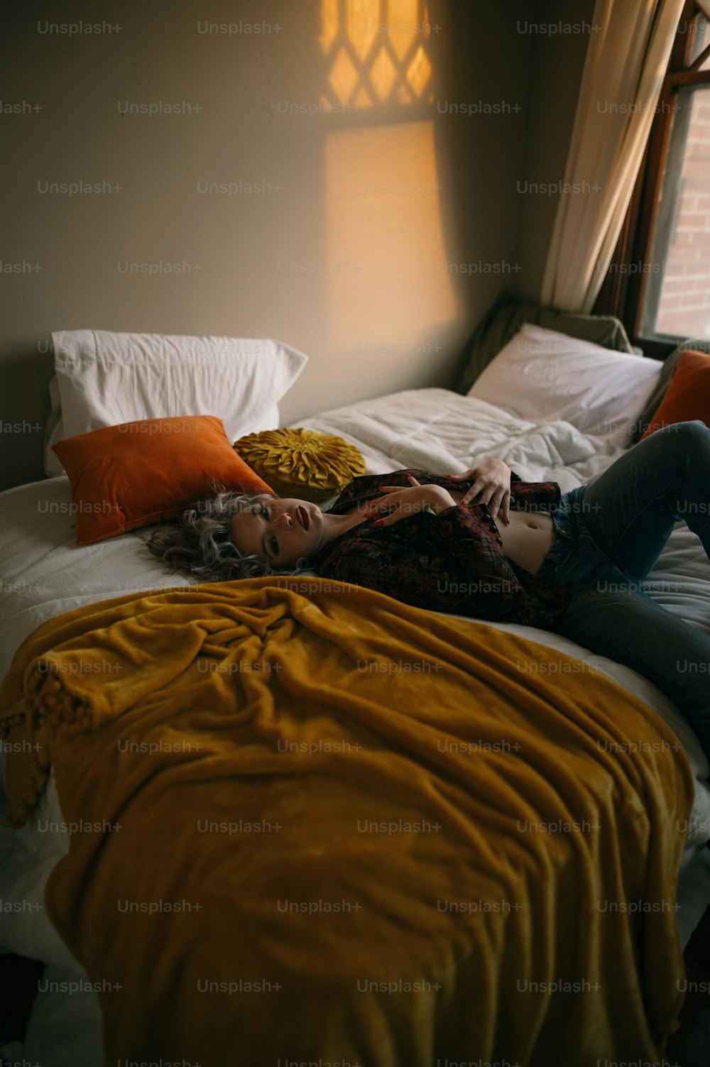 une femme allongée sur un lit à côté d’une fenêtre