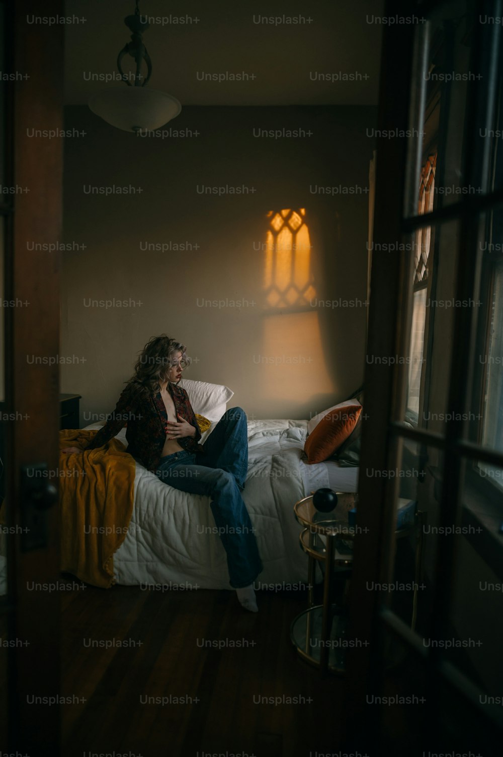 uma mulher sentada em uma cama em um quarto escuro