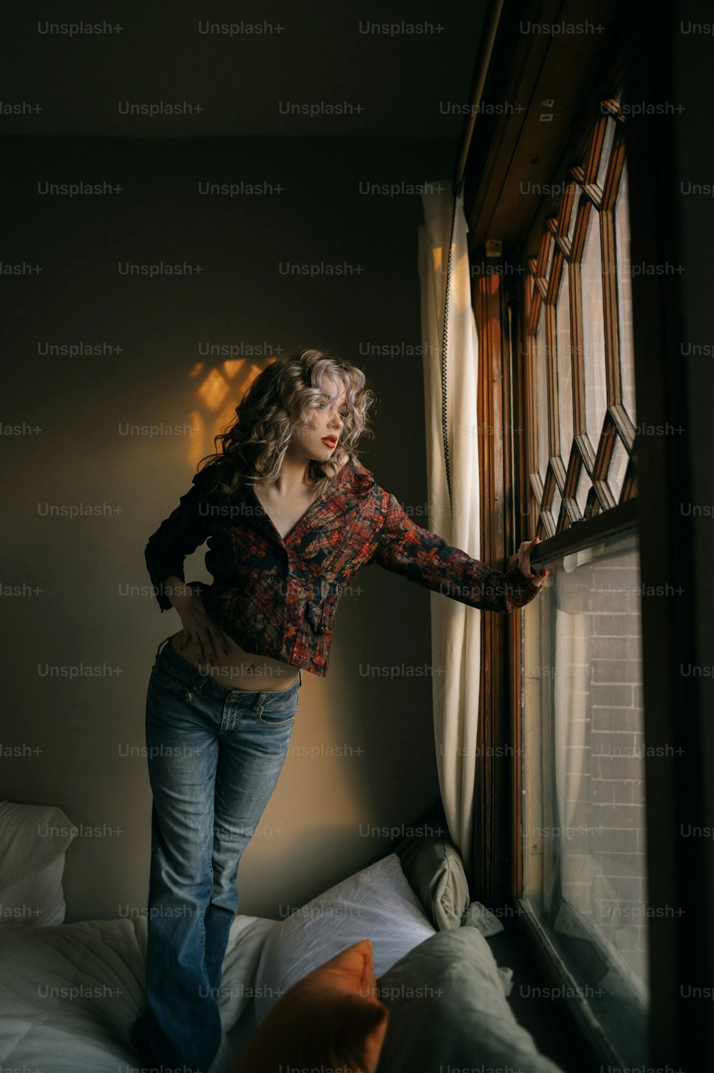 Una donna in piedi accanto a una finestra in una camera da letto