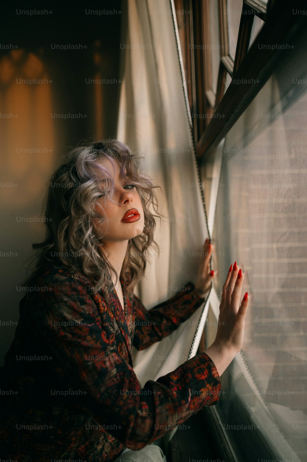 Une femme regarde par une fenêtre