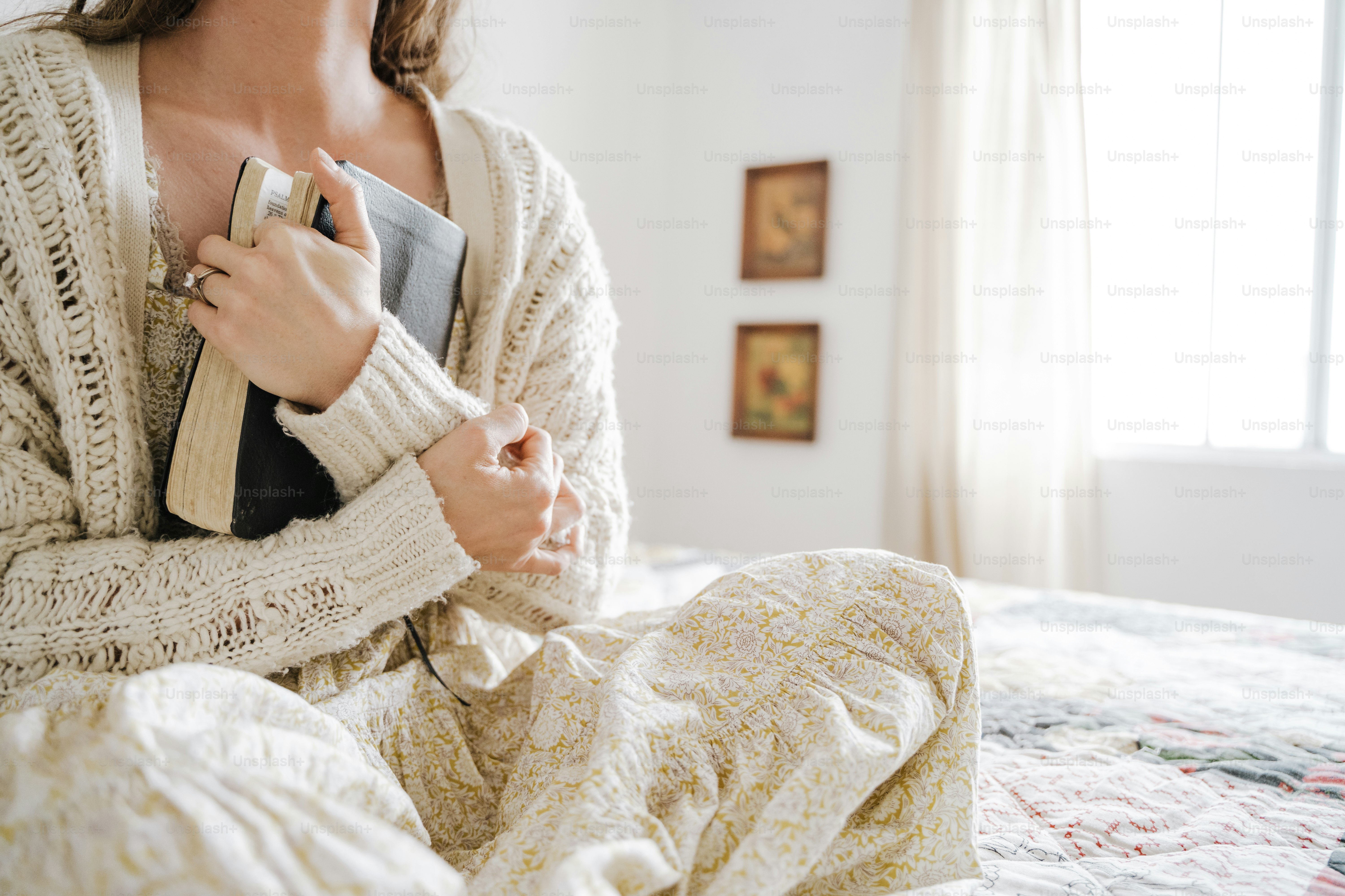 a woman sitting on a bed holding a book
