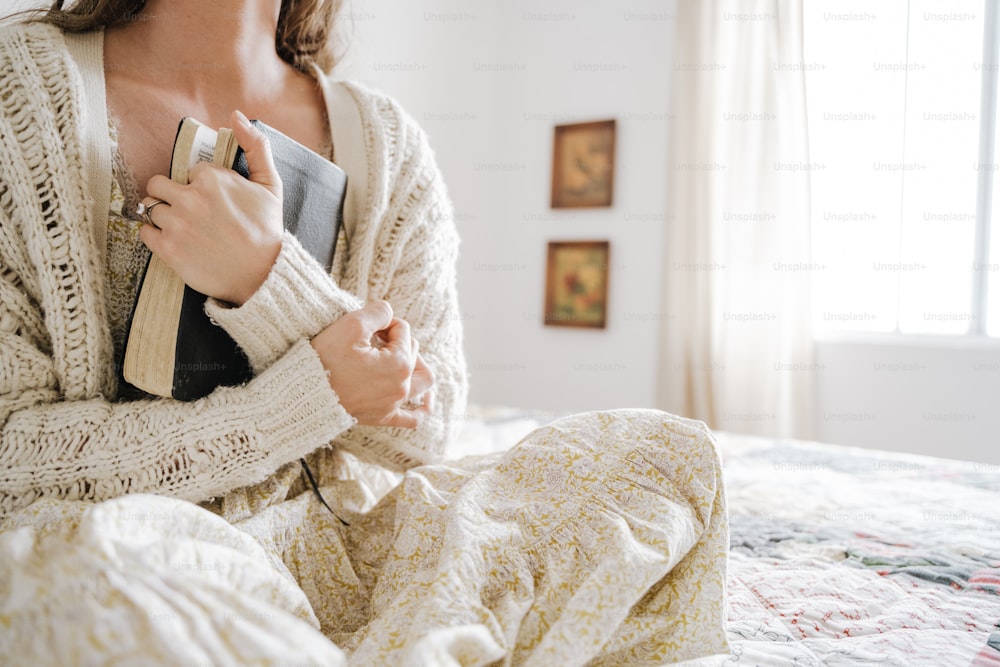 Una mujer sentada en una cama sosteniendo un libro