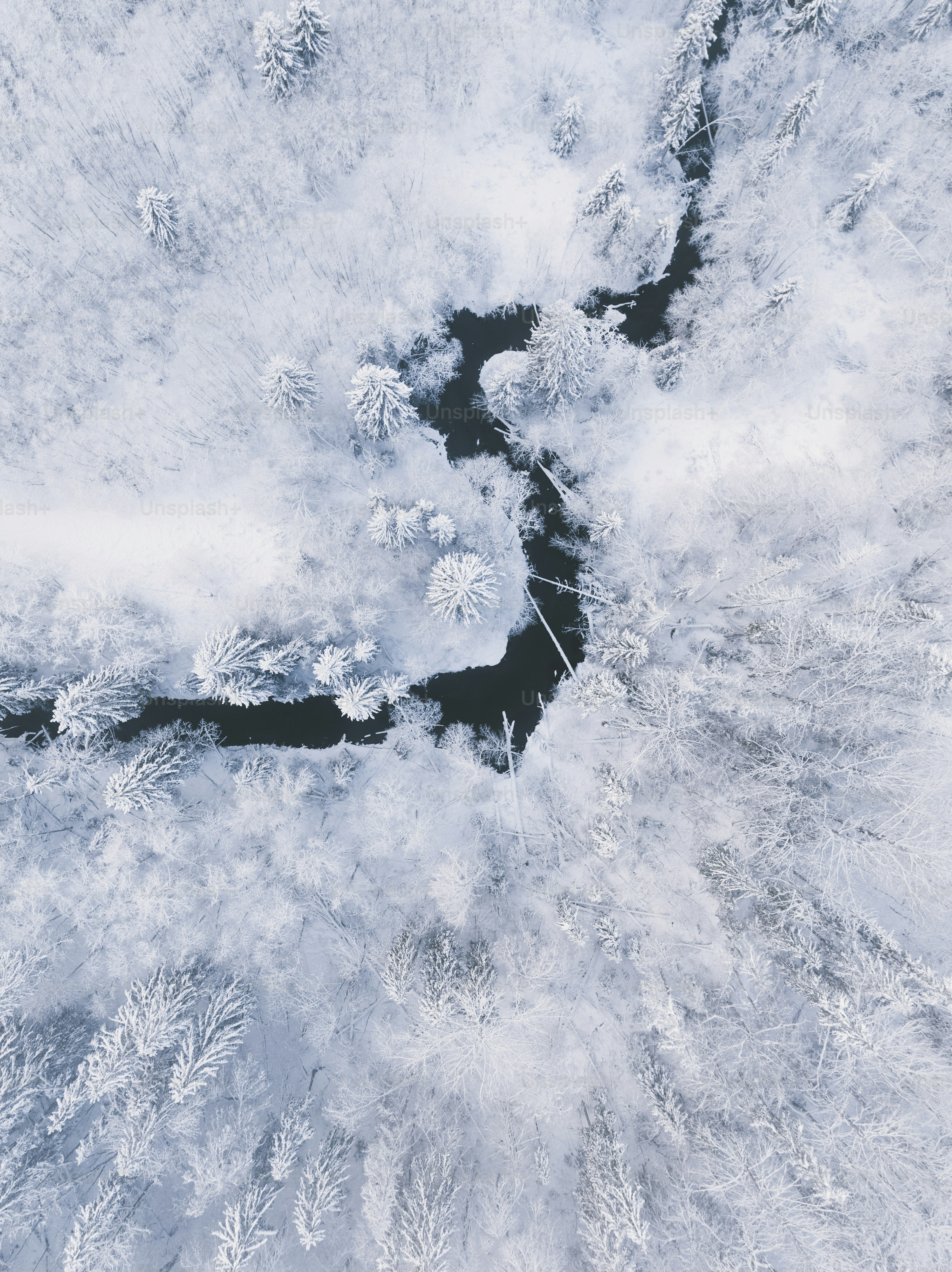 an aerial view of a river surrounded by snow