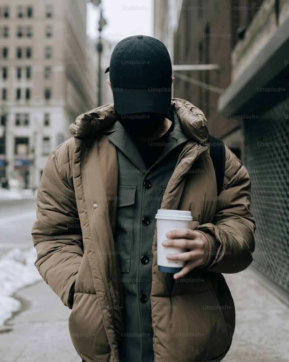 um homem andando por uma rua segurando uma xícara de café