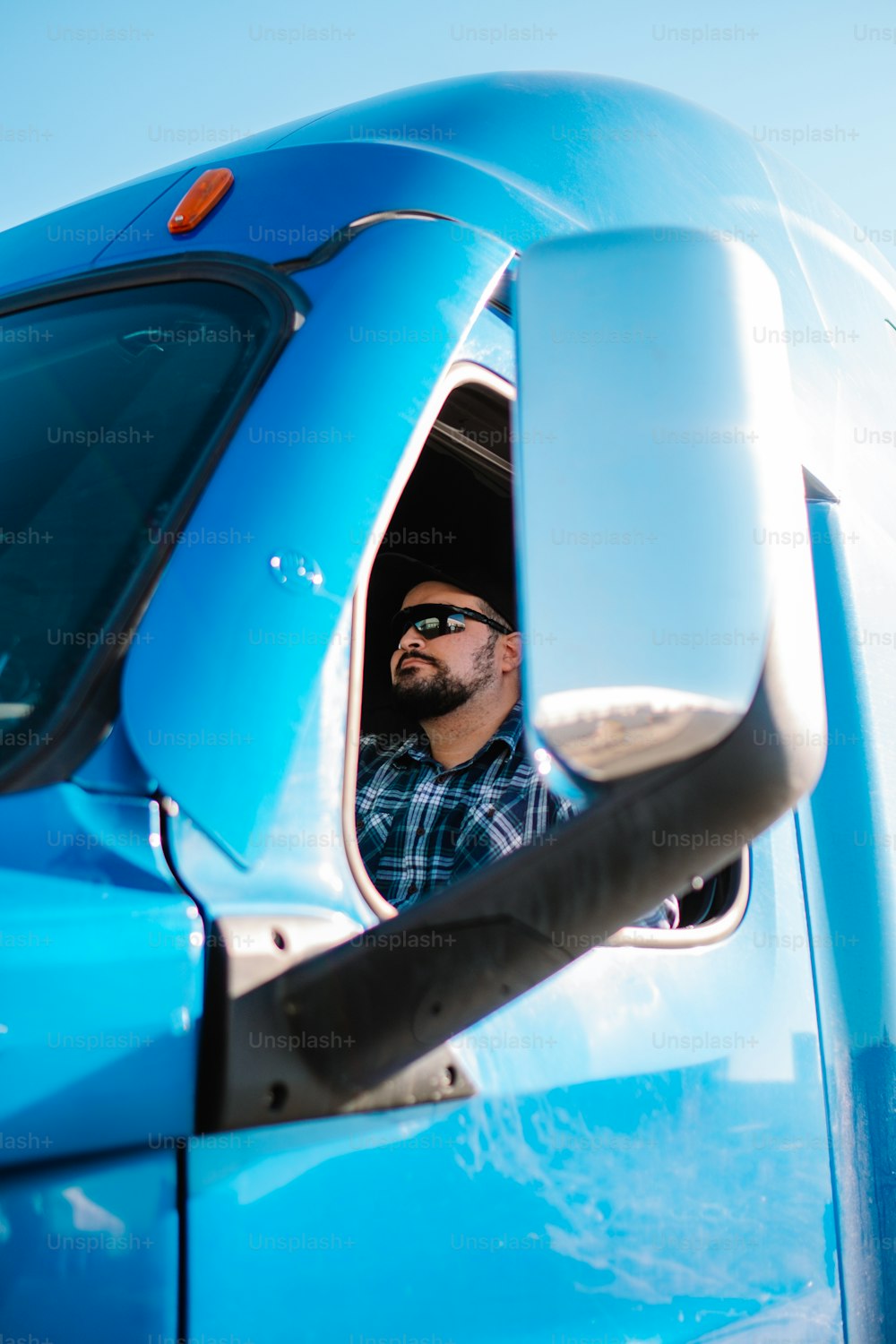 a man looking out the window of a blue truck