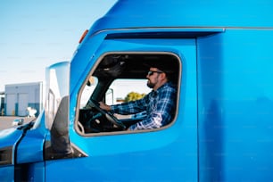 a man sitting in the drivers seat of a blue truck