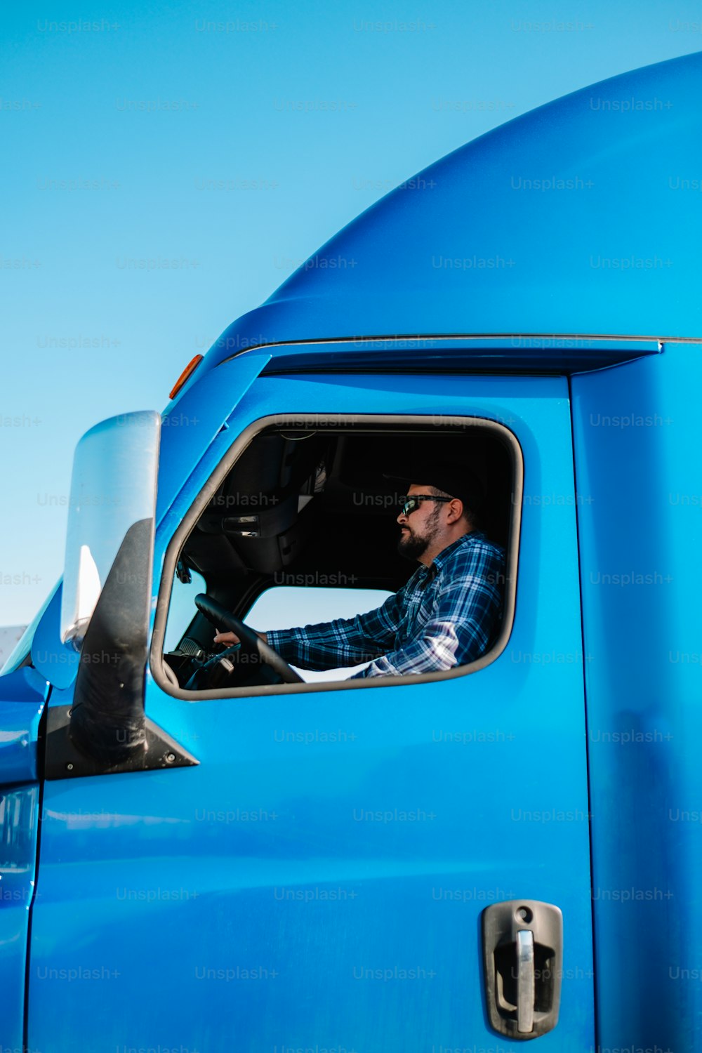Ein Mann sitzt auf dem Fahrersitz eines blauen Lastwagens