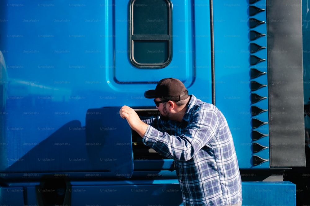 青いトラックの隣に立つ男