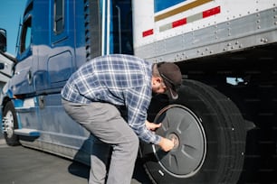 한 남자가 세미 트럭의 타이어를 바꾸고 있다