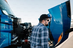 a man standing next to a blue semi truck