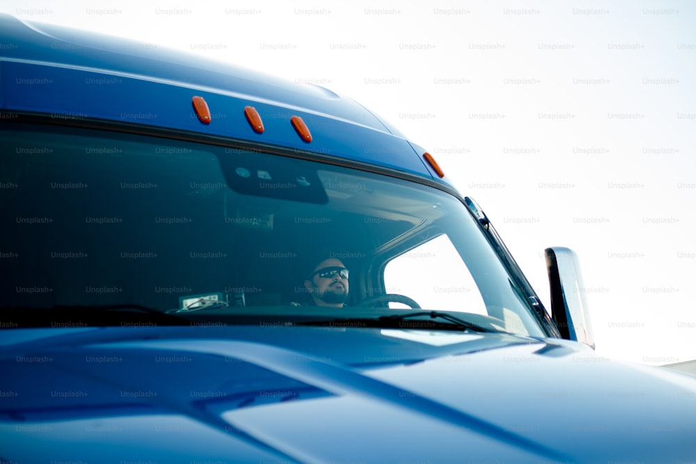 a man sitting in the drivers seat of a blue truck