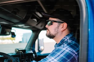 a man driving a truck wearing a hat and sunglasses