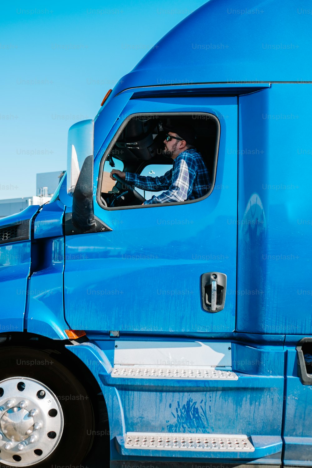 um homem dirigindo um caminhão semi azul em um estacionamento