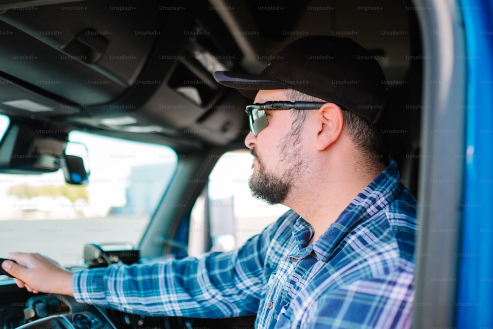 um homem dirigindo um caminhão usando óculos escuros e um chapéu