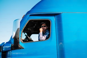 Ein Mann sitzt auf dem Fahrersitz eines blauen Lastwagens