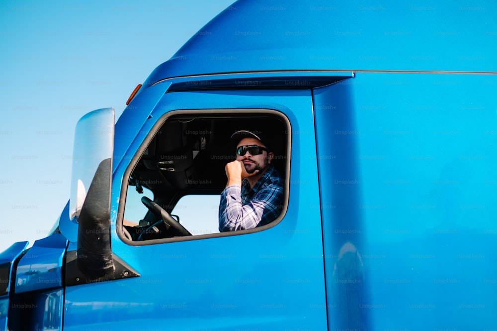 Un uomo seduto al posto di guida di un camion blu