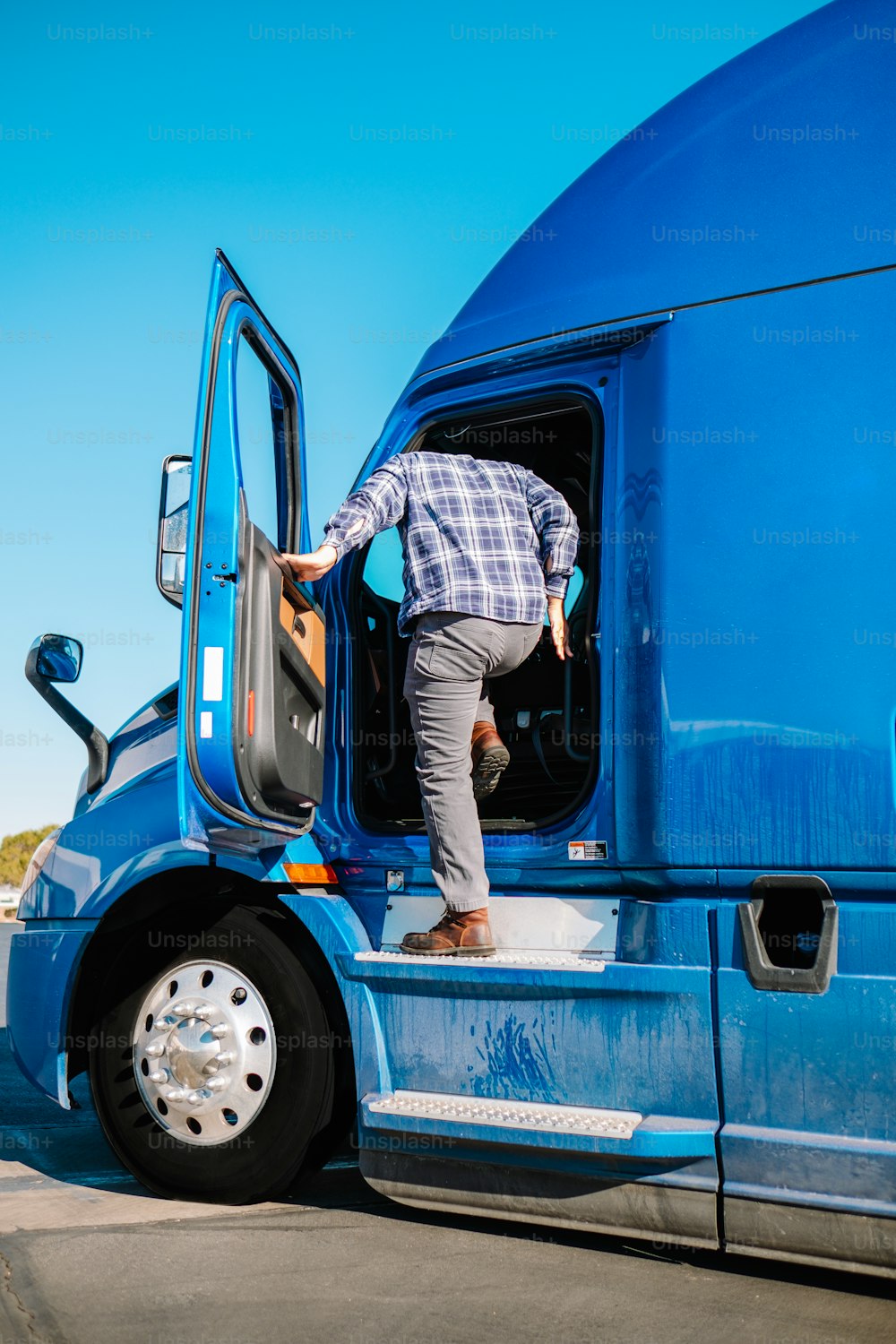 a man standing on the door of a blue semi truck