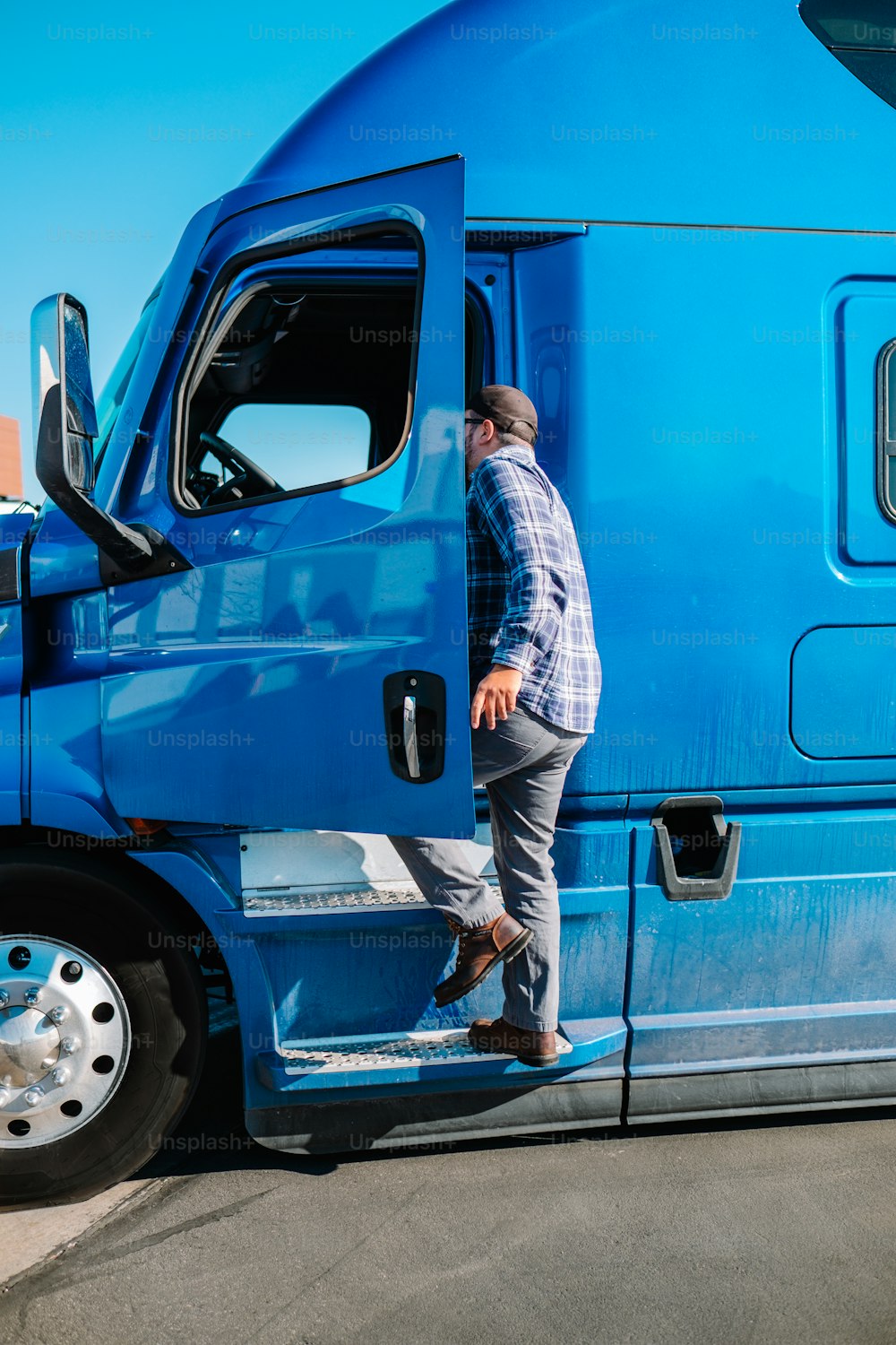 a man standing on the door of a blue semi truck