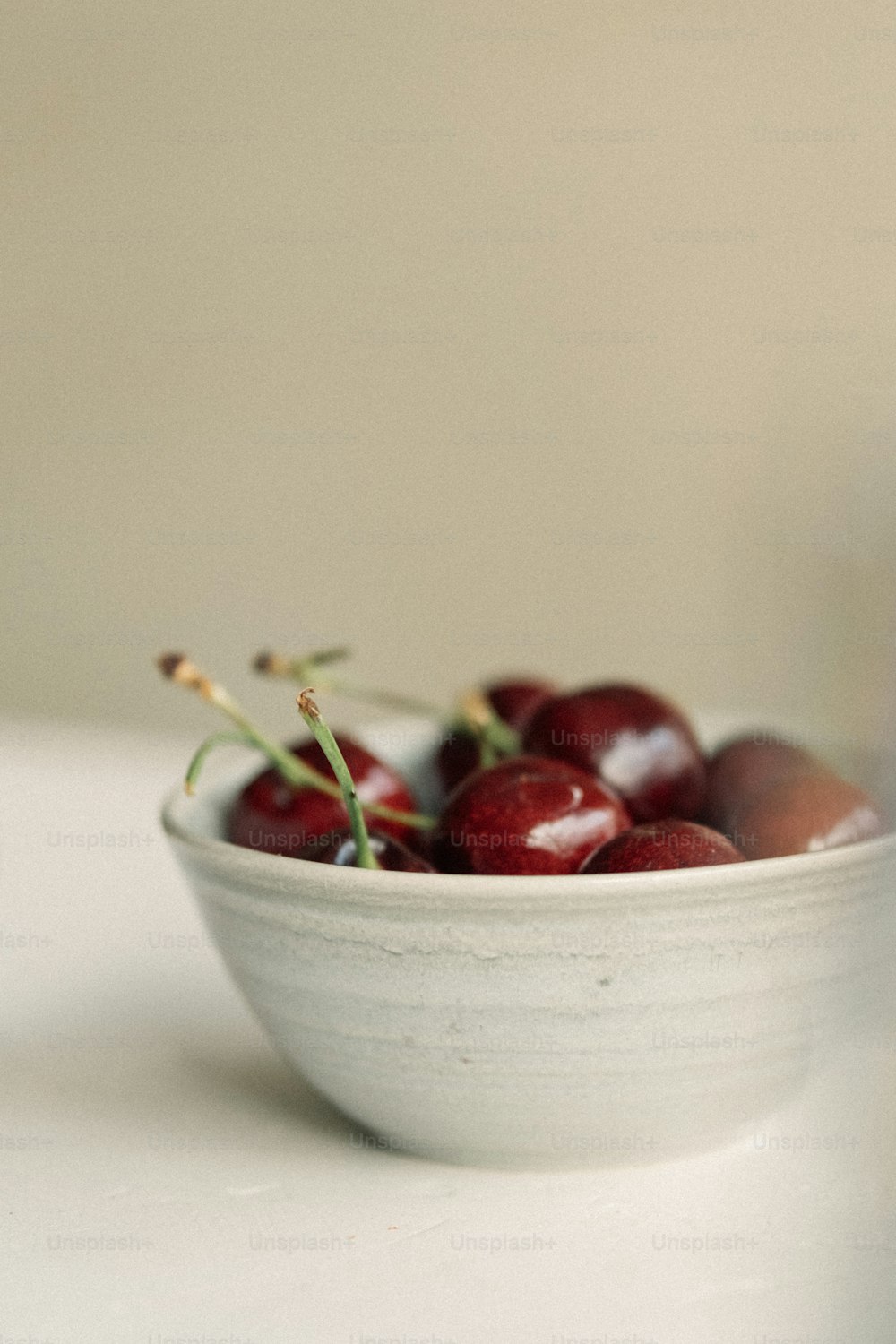 a white bowl filled with cherries on top of a table