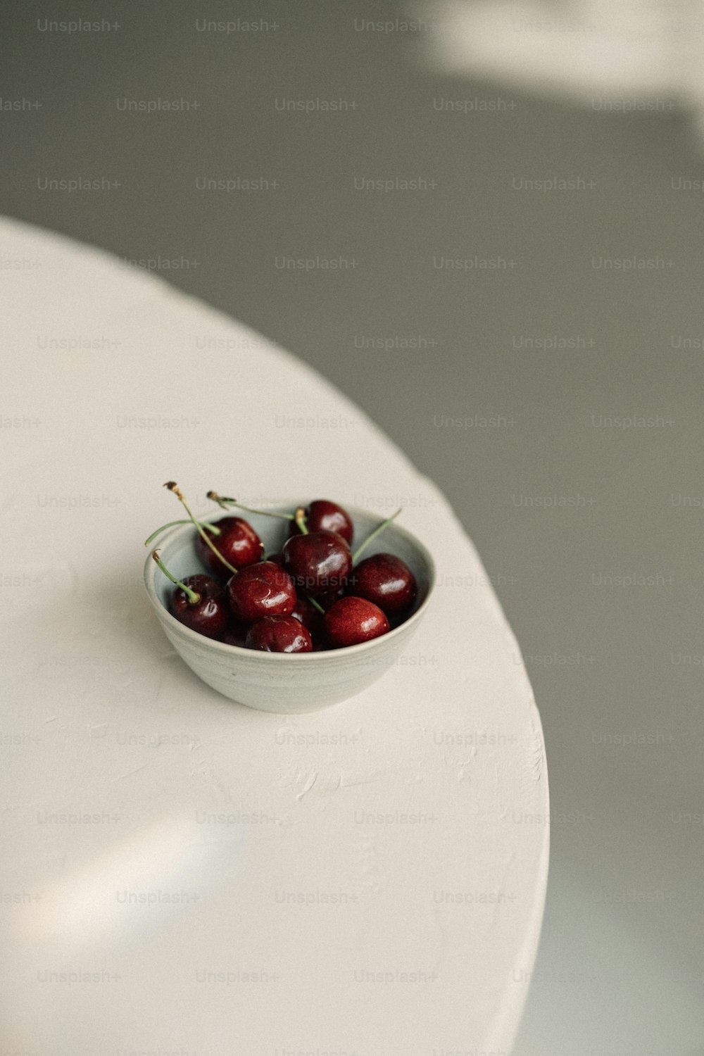 a bowl of cherries on a white table