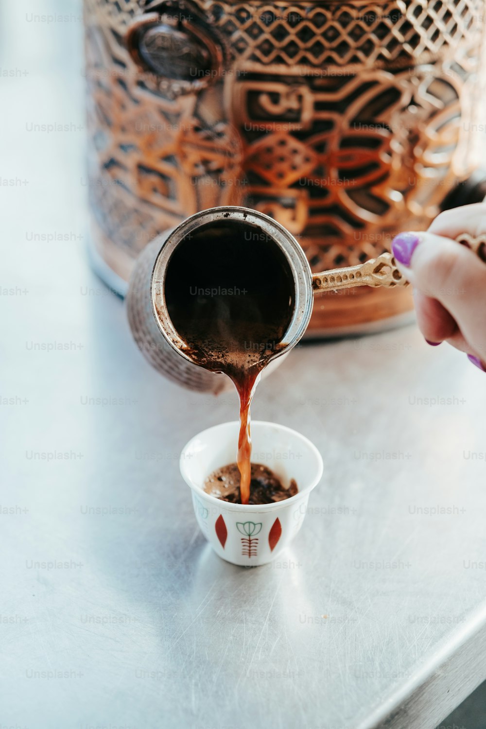 a person pours coffee into a small cup