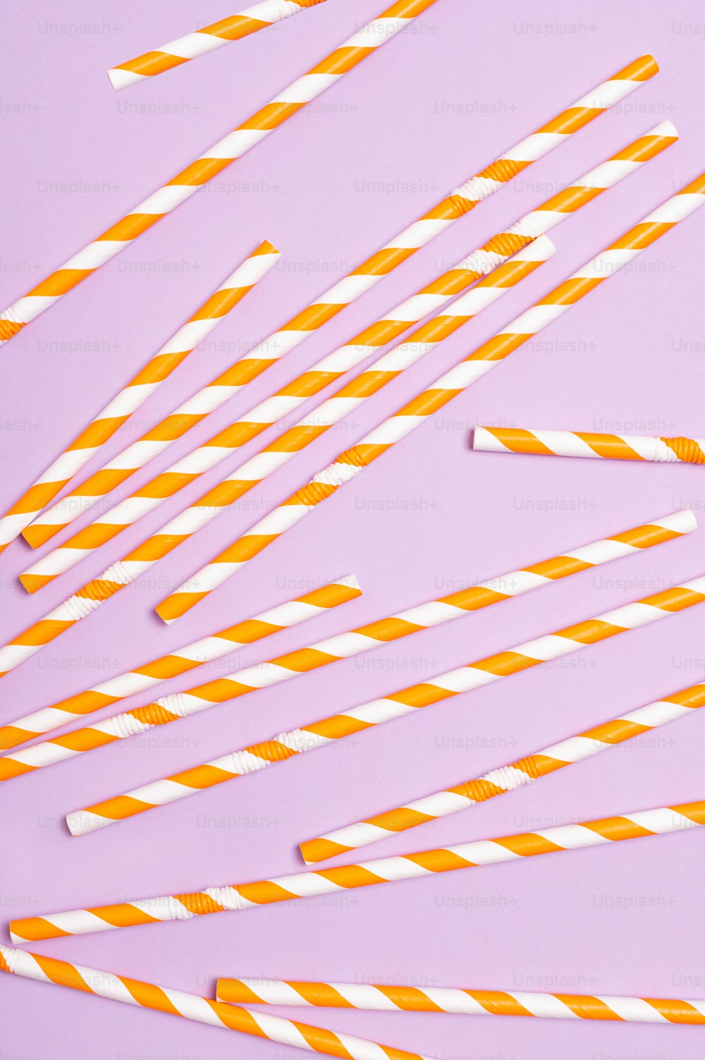 orange and white striped paper straws on a purple background