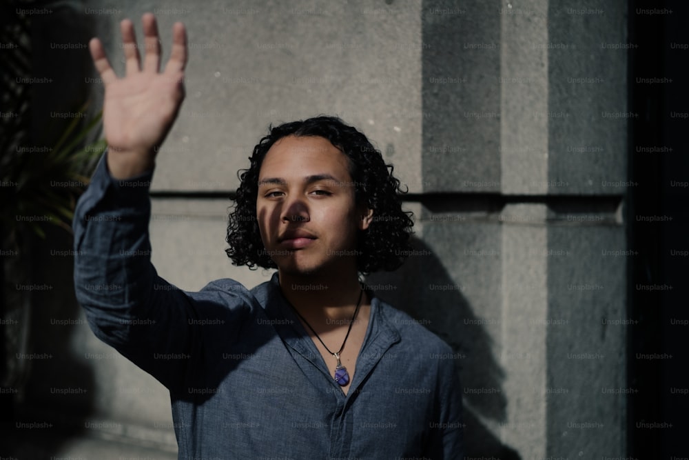 a man with curly hair waves to the camera