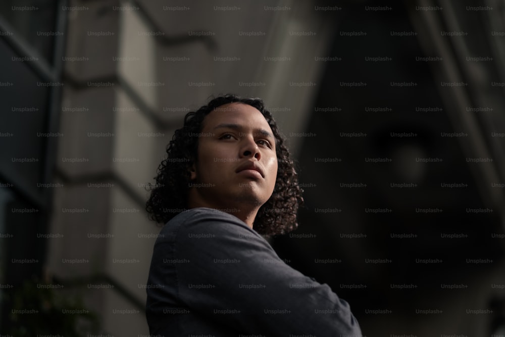 a man with curly hair standing in front of a building