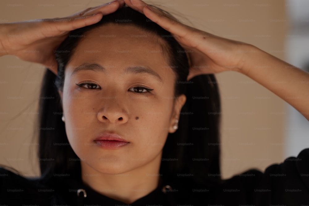 a woman holding her hands up to her head