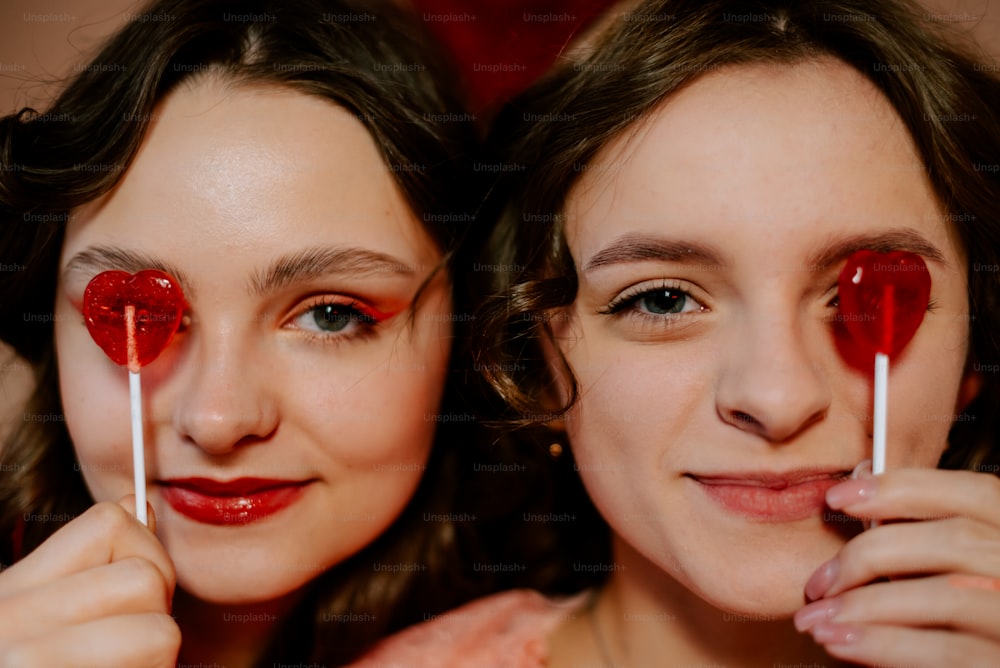 duas mulheres jovens segurando pirulitos em suas bocas