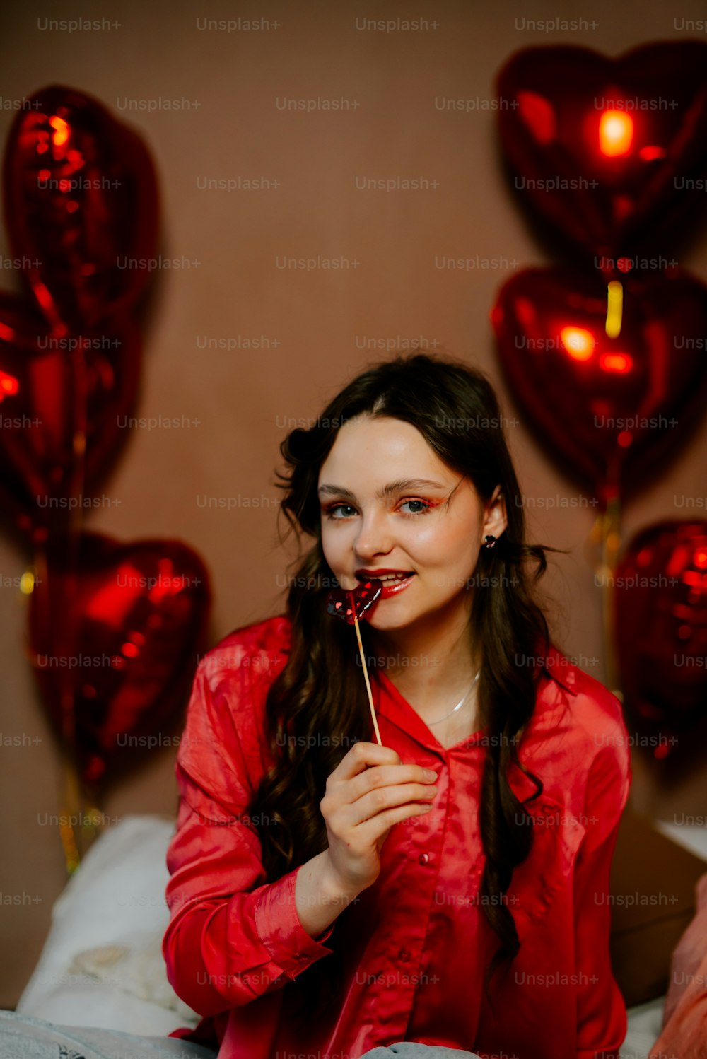 a woman in a red shirt holding a lollipop