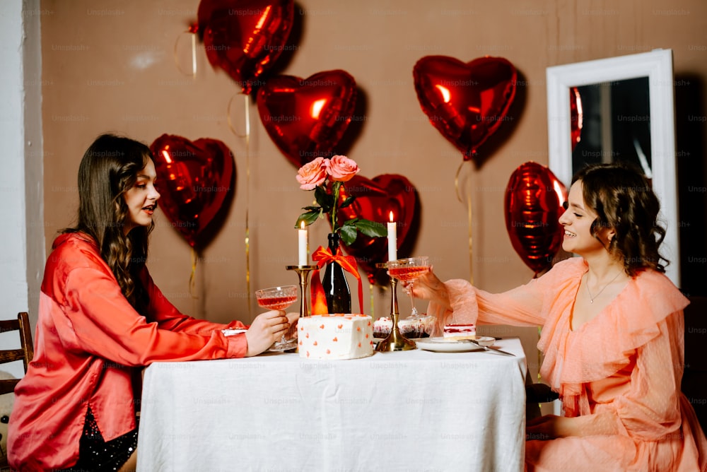 Un par de mujeres sentadas en una mesa con un pastel