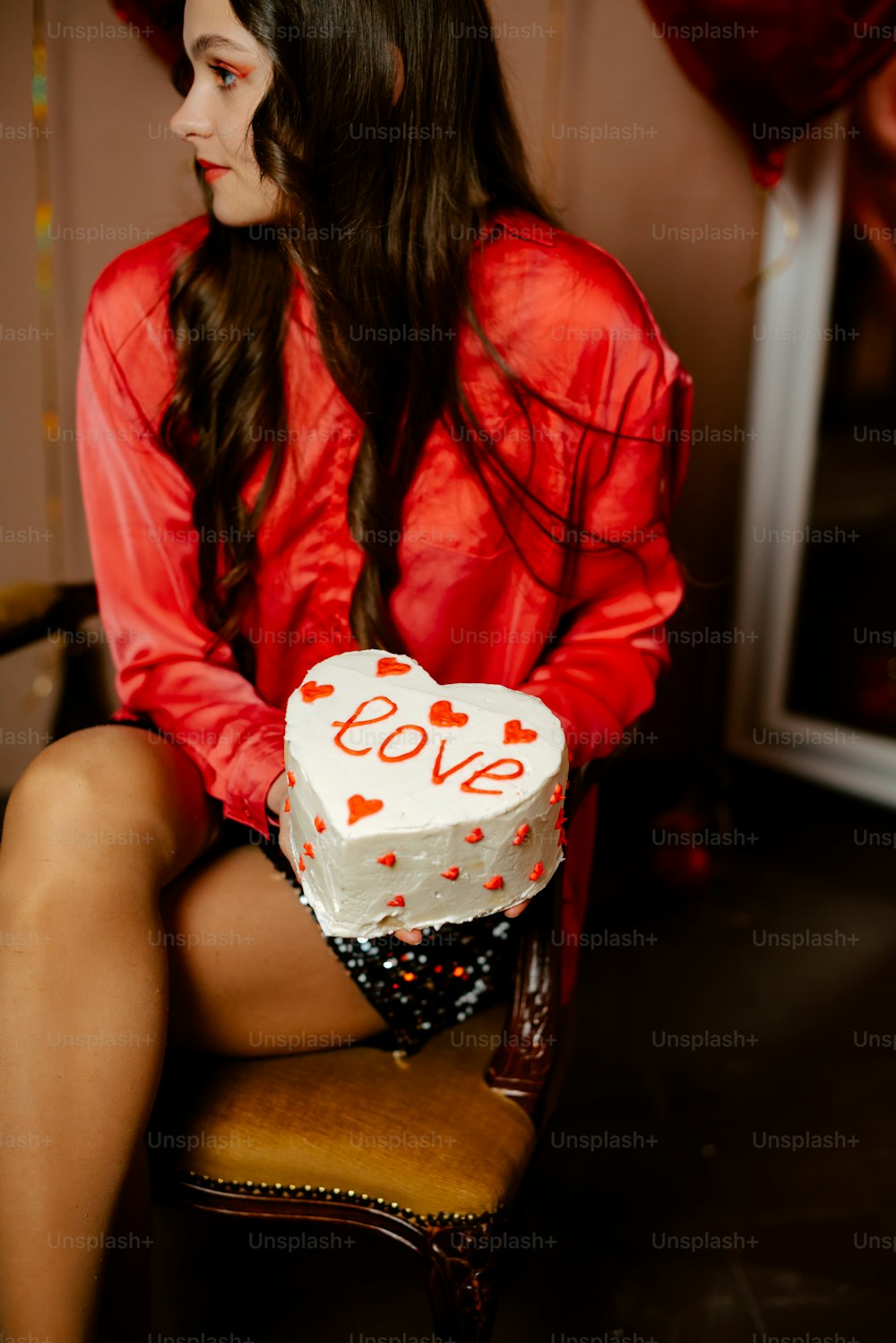 a woman sitting on a chair with a cake in front of her