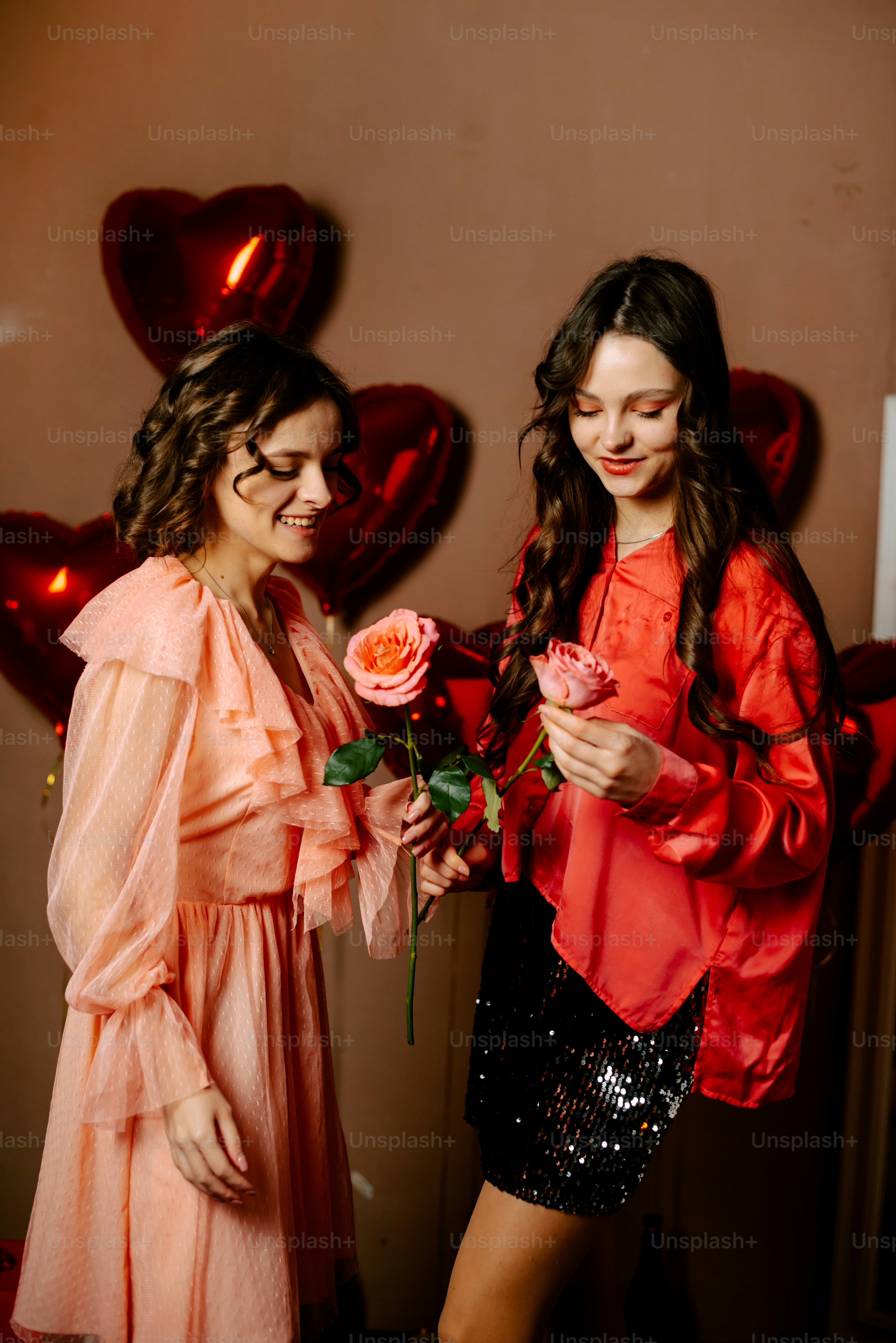 two young women standing next to each other holding roses