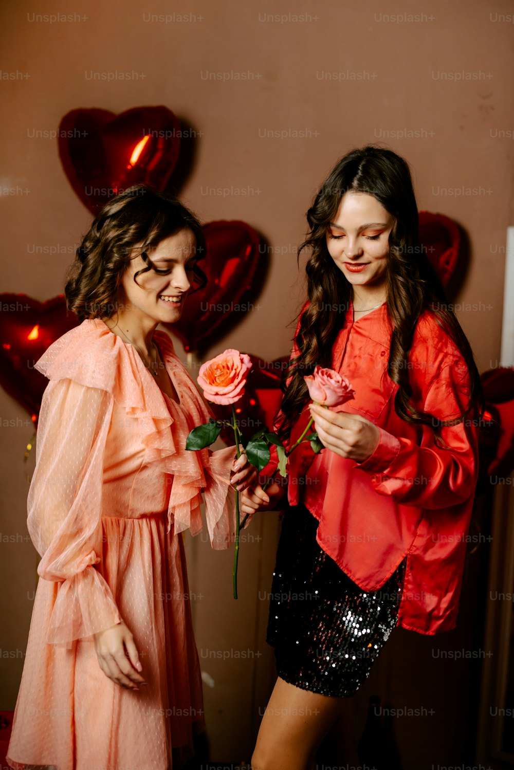 two young women standing next to each other holding roses