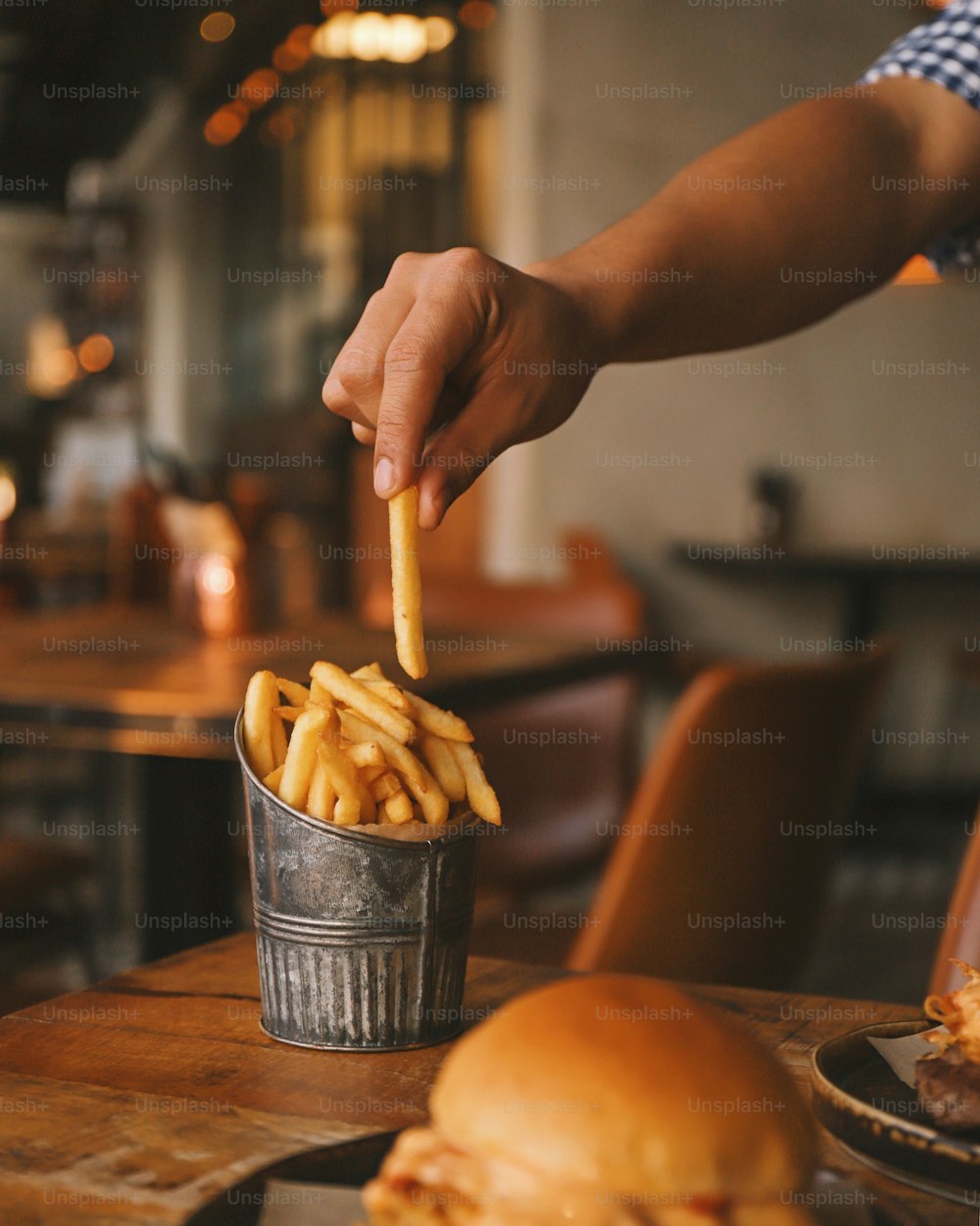 a person holding a piece of french fries in a bucket