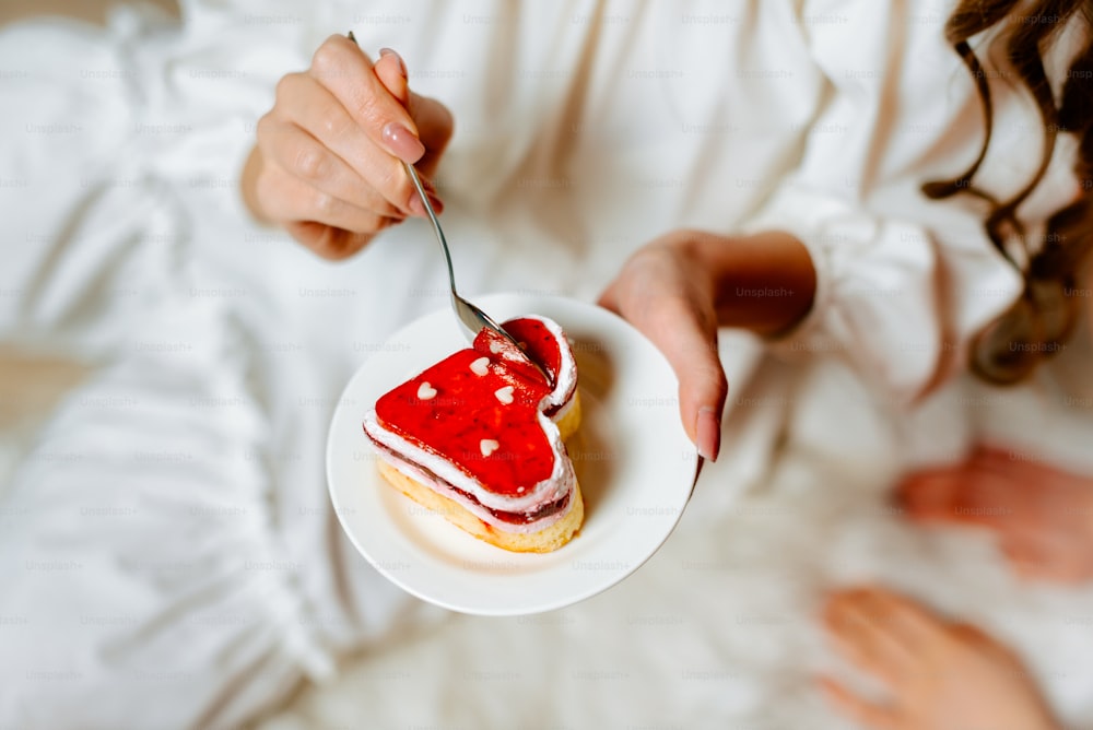 a woman holding a plate with a piece of cake on it