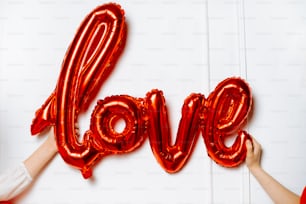 uma pessoa segurando um balão vermelho na forma da palavra amor