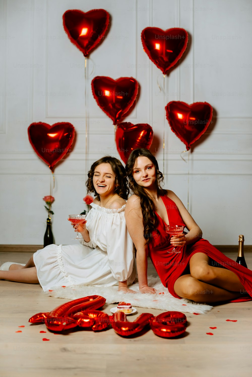 two women sitting on the floor with red balloons