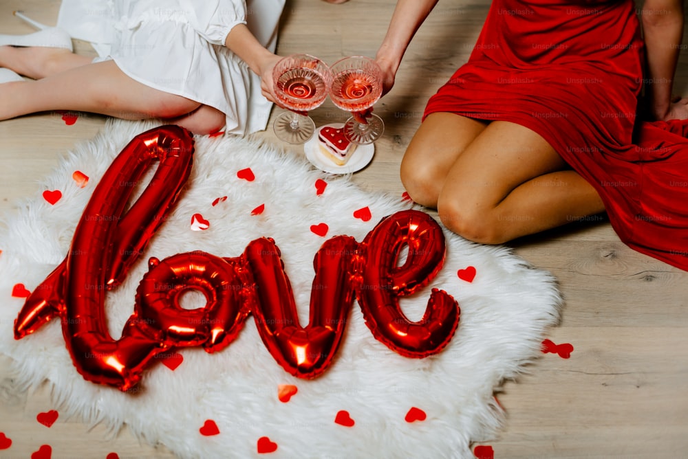 two women sitting on the floor holding glasses of wine with the word love spelled out