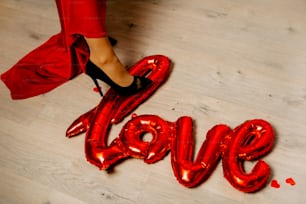 Les pieds d’une femme et les ballons rouges épelant l’amour