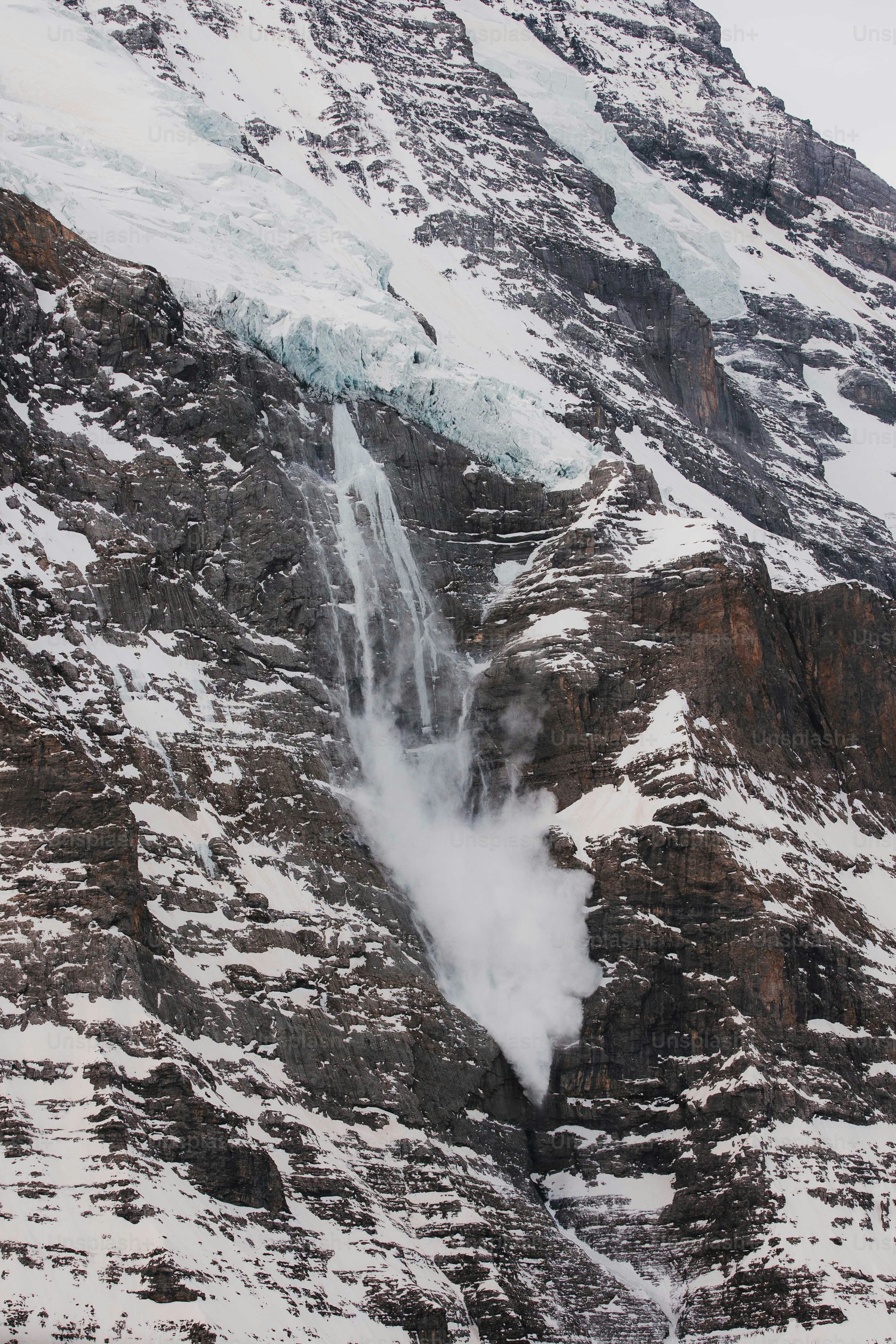 a snow covered mountain with a waterfall coming out of it