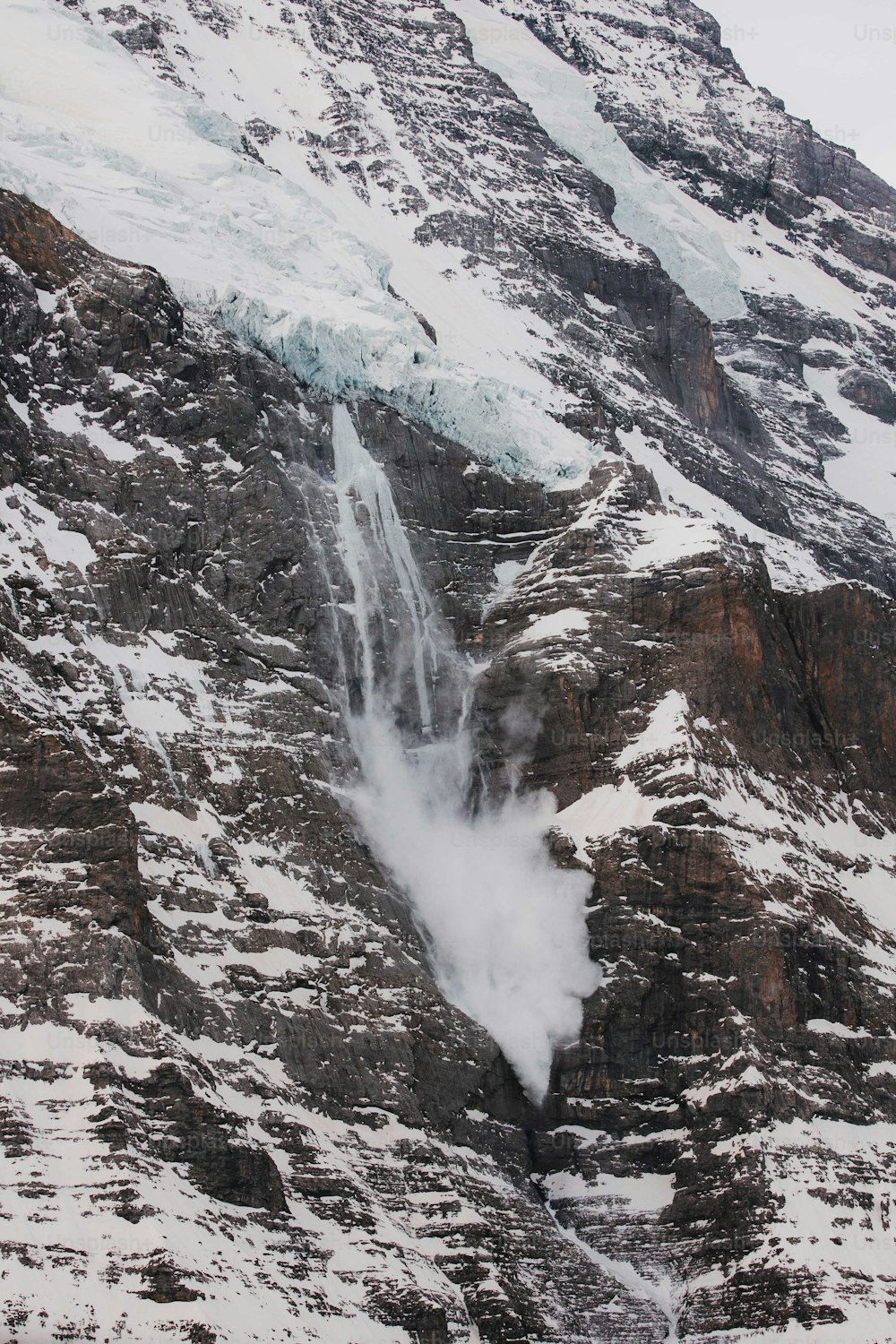 uma montanha coberta de neve com uma cachoeira saindo dela
