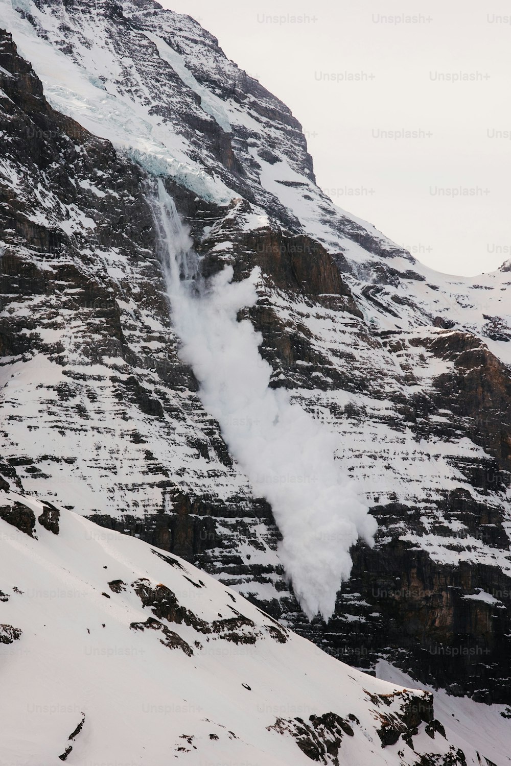 a snow covered mountain with a small stream of water coming out of it