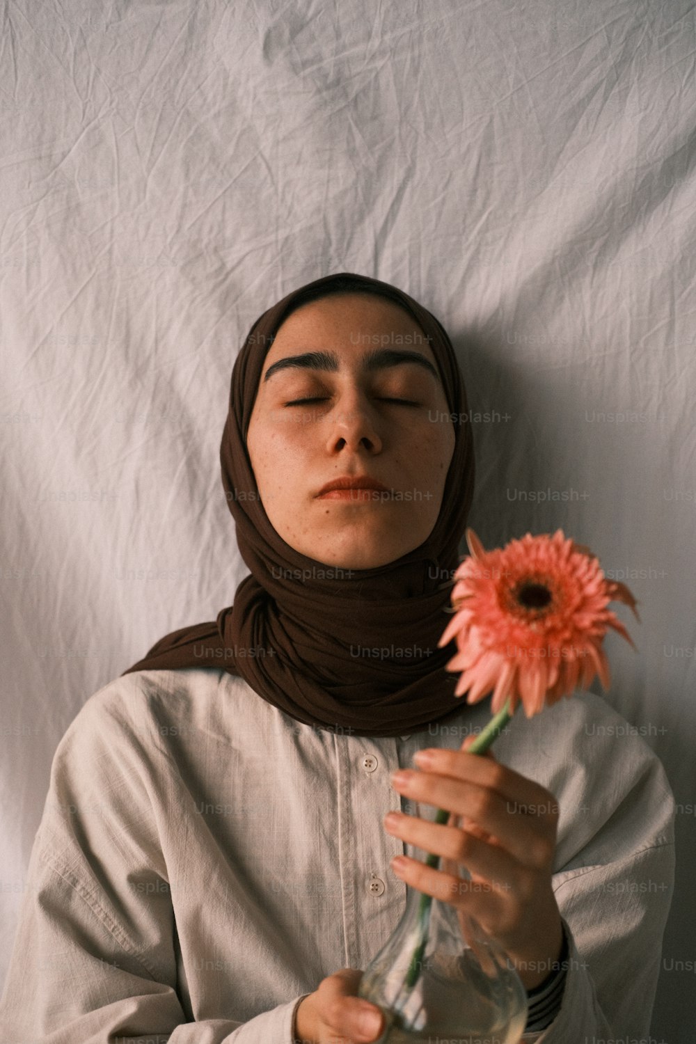 a woman in a hijab is holding a flower