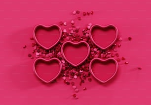 Un montón de cortadores de galletas en forma de corazones sobre un fondo rosa