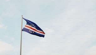 a flag flying in the wind with a blue sky in the background