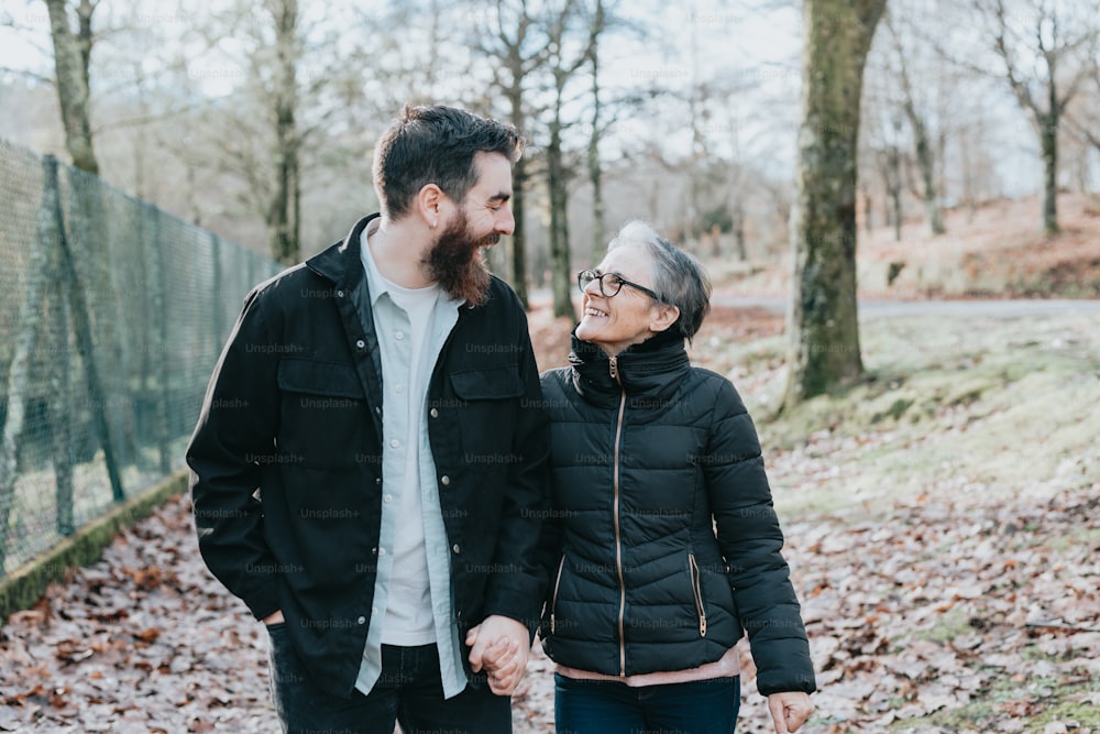 Ein Mann und eine Frau, die Händchen halten und im Wald spazieren gehen