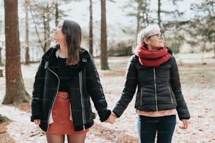 two women holding hands and walking through the woods