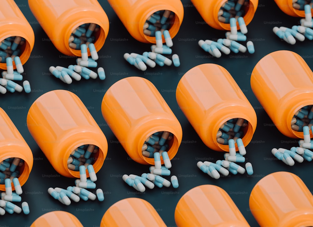 Un gruppo di flaconi di pillole arancioni pieni di pillole blu e bianche